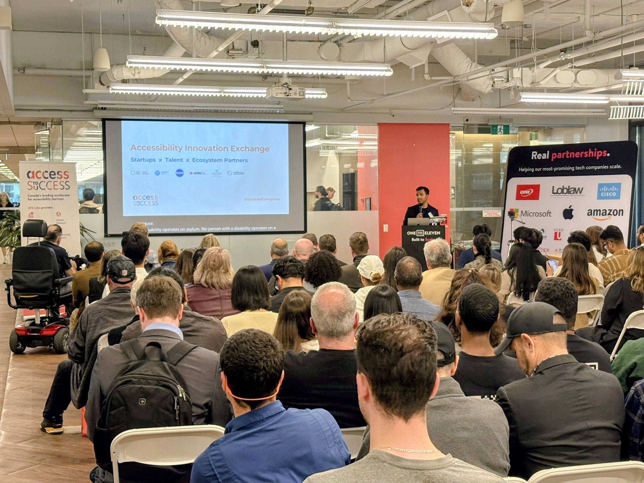 A man at a podium speaking about The Accessibility Innovation Exchange