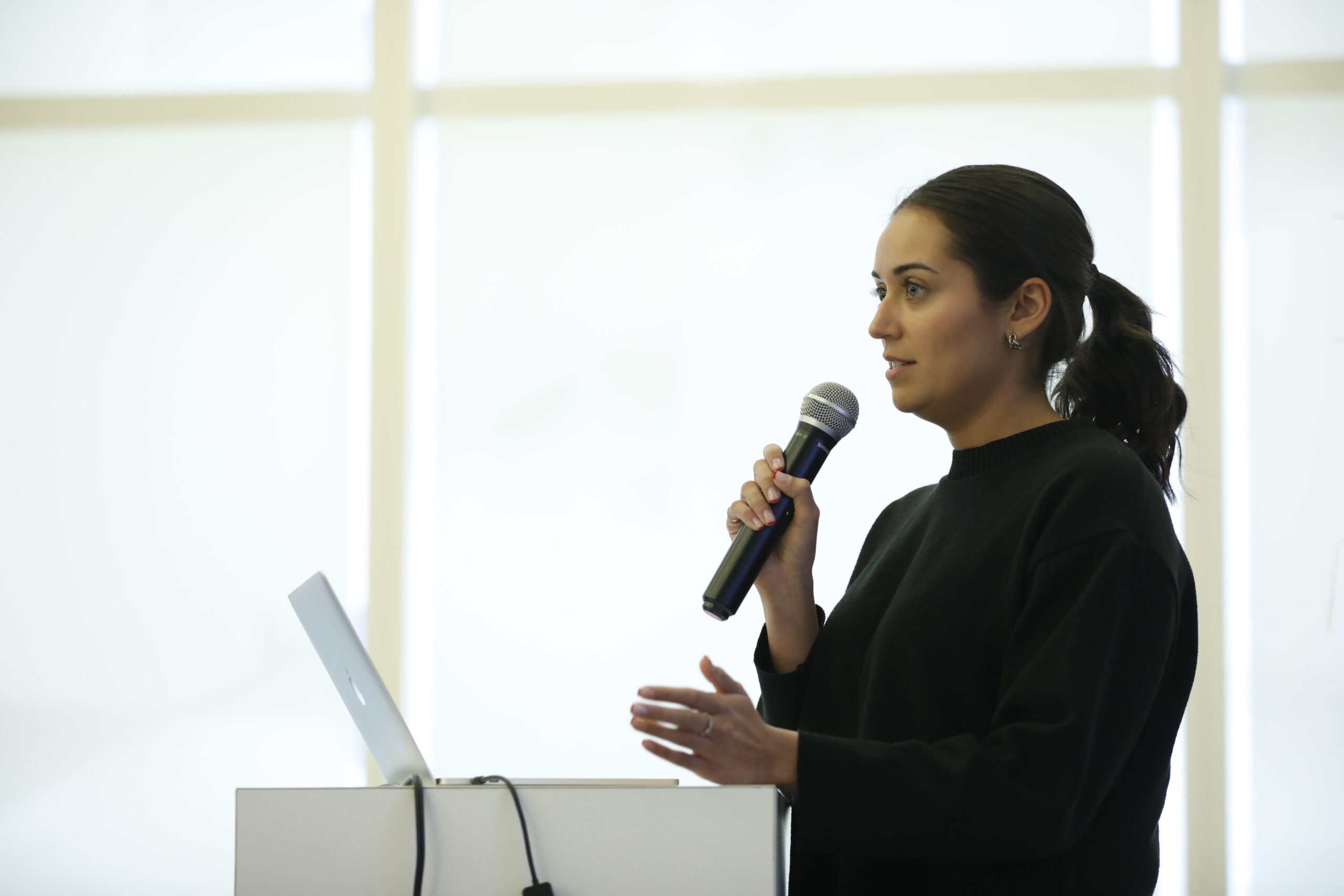 A young woman speaking at a podium holding a microphone