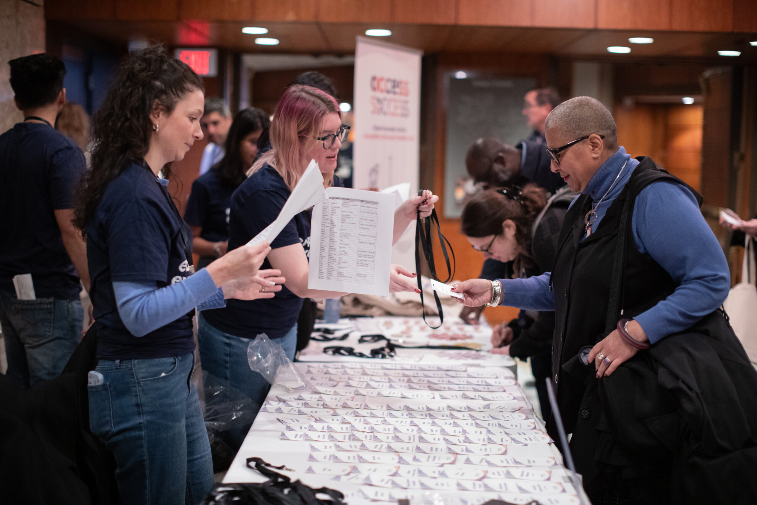 A young volunteer handing out badges at an Access to Success event