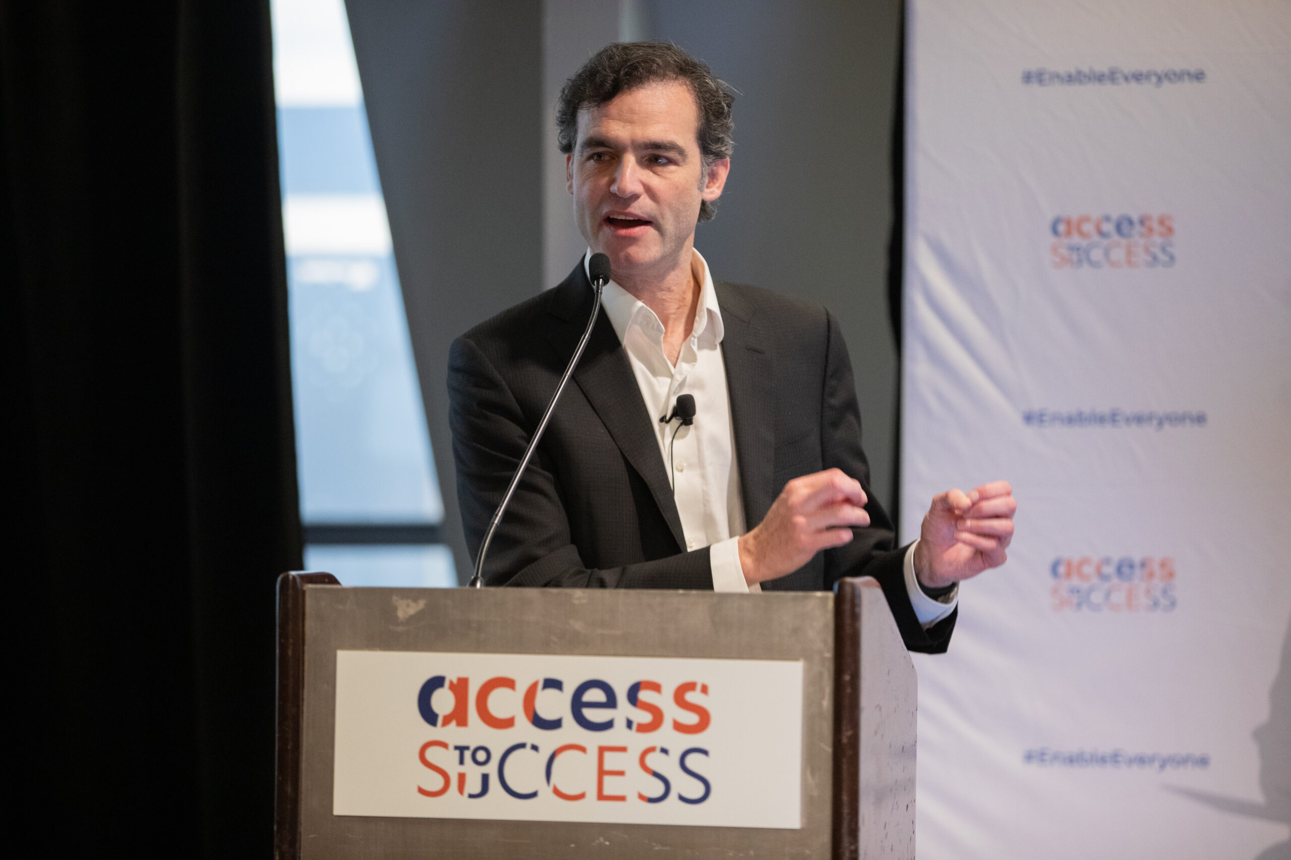 A gentleman in a suit speaking at a podium at an Access to Success event