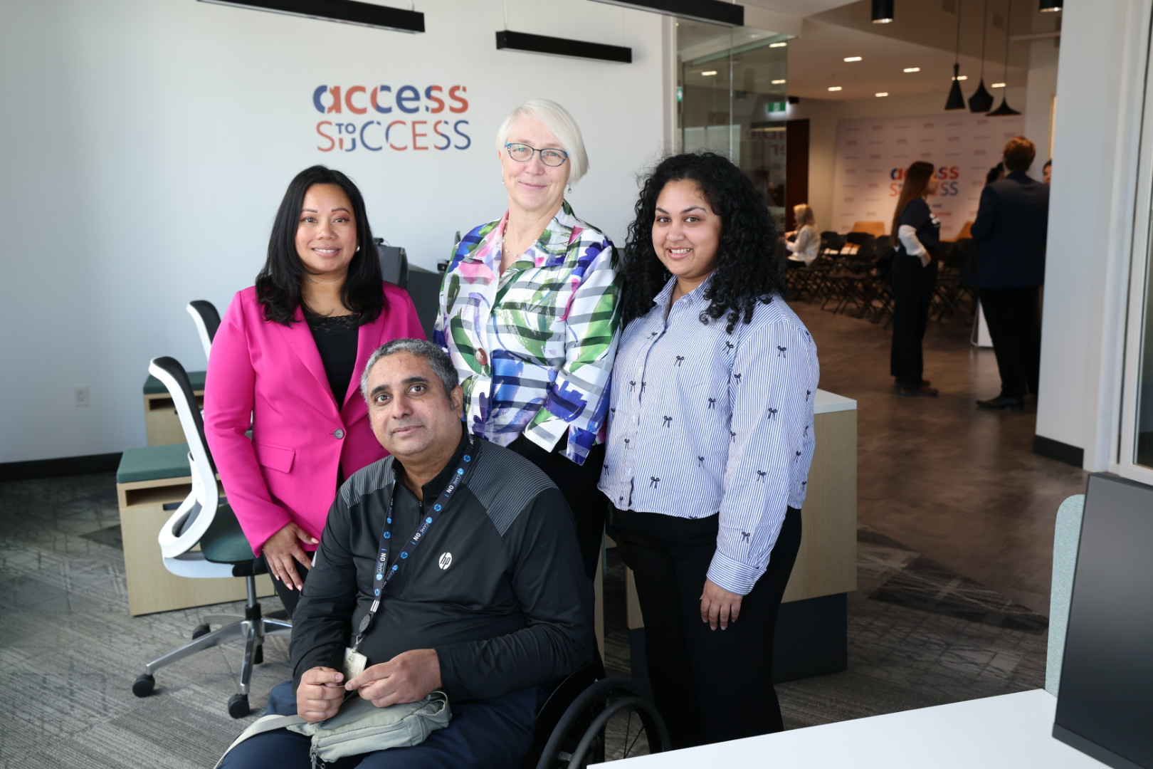 4 people smiling at the entrance of Access to Success labs office space.